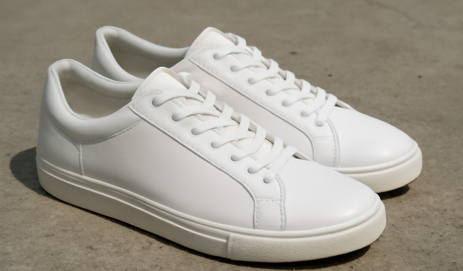 paire de sneakers blanches posees sur beton